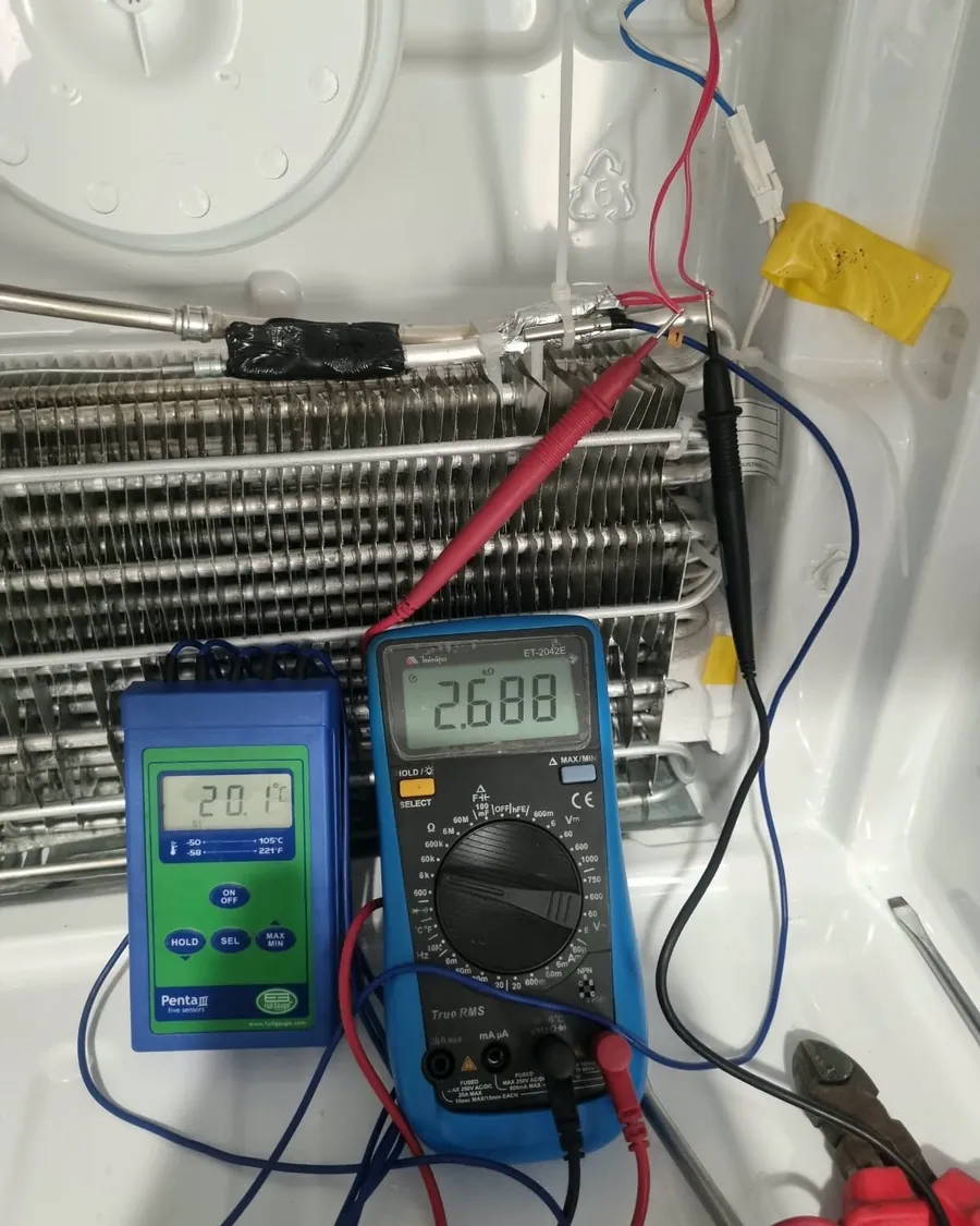 Técnico medindo o sensor da geladeira com multímetro e termômetro
